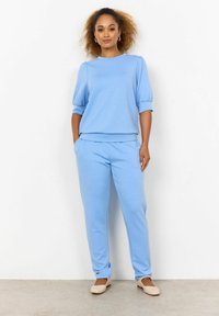 Világoskék loungewear szett, rövid ujjú, kerek nyakú toppal és gumírozott mandzsettákkal, párosítva az azonos mintájú gumírozott derekú nadrággal.