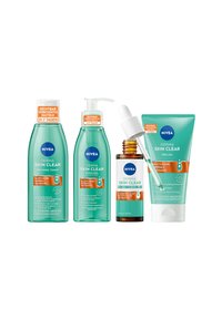 Four NIVEA skincare products in aqua-colored bottles: refining toner, cleansing gel, serum, and peeling cream; all with orange accents and text labels.