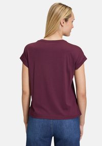 Burgunderfarbenes T-Shirt mit kurzen Ärmeln und Rundhalsausschnitt, aus weichem Stoff. Die Rückansicht zeigt eine lässige Passform mit abgerundetem Saum.