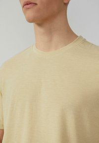 Lichtgele T-shirt met korte mouwen van zachte stof, met een klassieke ronde hals en subtiele textuurdetails.