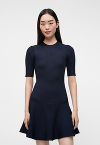Vestido de color azul marino con corsé ajustado y falda acampanada, mangas cortas, tejido texturizado y patrón horizontal en la línea de la cintura.