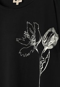 Tissu noir avec un dessin au trait blanc de deux fleurs abstraites et des feuilles, une complètement ouverte et une en bouton.