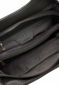 Interno di una borsa in pelle nera con due scomparti con zip e una fodera in tessuto grigio, con etichetta del marchio Surifrey.