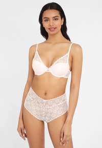 Helle rosa Spitzen-BH und passende hochgeschnittene Slips mit Floralmotiv, gewellten Kanten und einem kleinen Schleifenakzent in der Mitte.
