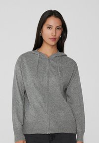 Sudadera con cremallera en color gris, con una textura suave, cordones ajustables, puños y dobladillo acanalados. Fabricada con un tejido ligero y cálido.