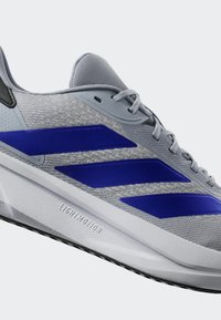 Lightweight gray athletic shoes with mesh upper, three prominent blue stripes, textured design, and white sole labeled "LIGHTMOTION."