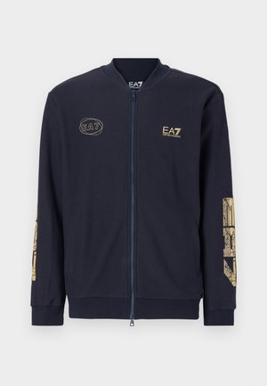 Marineblauwe zip-up jack van textiel. Heeft een gouden EA7-logo en grafisch ontwerp op de mouwen. Inclusief zijzakken en ribgebreide manchetten.