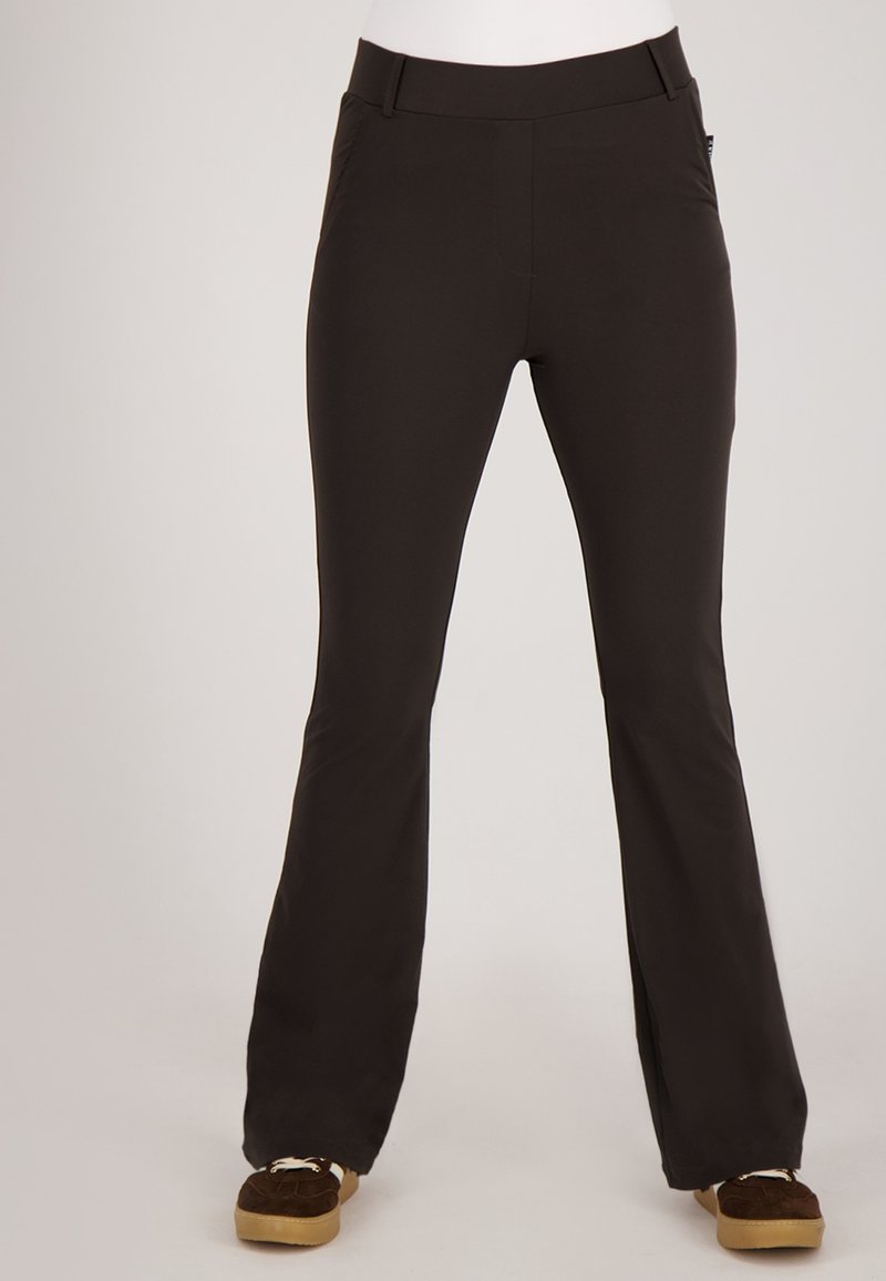 Zwarte flared broek met een gladde textuur, voorzien van een platte tailleband en zijzakken. Draagt bij bruine suède schoenen.