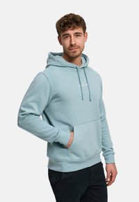 Ljusblå hoodie i mjuk bomullsblandning med framficka och logotyp på bröstet.