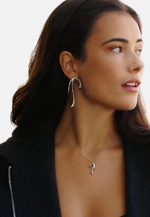 Silver earrings with a curved design, complemented by a matching silver necklace featuring a pendant shaped like a stylized hook.