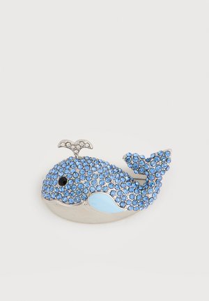 Broche en forme de baleine ornée de strass bleus et transparents, avec un œil noir et un détail de ventre bleu clair sur une base argentée.