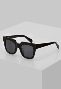 Black square sunglasses with dark lenses, glossy plastic frame, and thick arms. Notable square shape with rounded edges and minimal hardware.