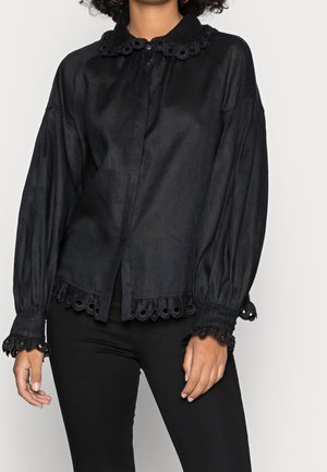 Camicia nera in lino a maniche lunghe con colletto arrotondato, caratterizzata da un bordo in occhielli ai polsi e all'orlo, e con chiusura frontale a bottoni.