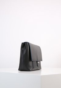 Borsa nera in pelle con un design strutturato, caratterizzata da una chiusura a patta e un'apertura in blu. Texture liscia con dettagli hardware minimi.