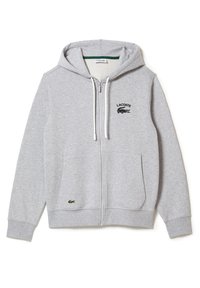 Sudadera gris con cremallera, hecha de una tela suave, con capucha, bolsillos frontales y un logo de Lacoste en negro. Incluye cordones blancos.