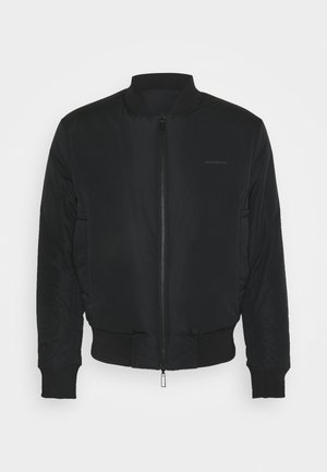 Veste bomber noire avec col, poignets et ourlet côtelés, avec une fermeture éclair à l'avant et des poches latérales.