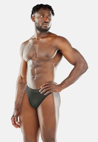Schwarze Herren-Thongs mit einem weichen Bund und einer glatten Textur, die ein enganliegendes Design und minimalen Komfort bieten. Keine Muster oder Akzente.