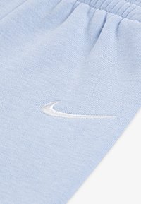 Light blue, soft fabric joggers with an elastic waistband. Features a white embroidered Nike logo on the front.