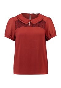 Blouse rouge avec manches bouffantes courtes, empiècement en dentelle au niveau de l'encolure et texture plissée. Dotée d'un col rond et d'une fermeture dos à fente.