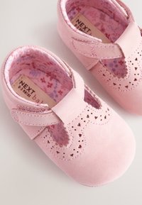 Scarpe da neonato in suede rosa con design a cinturino a T, bordi smerlati e perforazioni decorative. Foderate con tessuto a motivo floreale. Taglia 0-3 mesi.