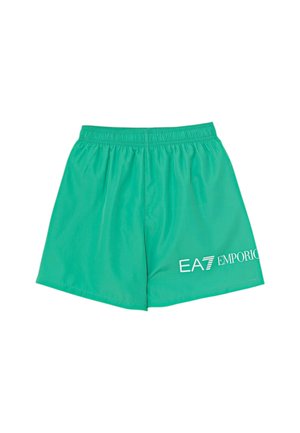 Pantaloncini sportivi verdi con vita elastica e logo bianco EA7 Emporio sulla parte inferiore della gamba destra su sfondo bianco.