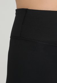 Czarne legginsy o wysokim stanie, wykonane z gładkiego, elastycznego materiału. Posiadają szeroki pas i płaskie szwy zapewniające wygodę.