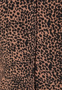 Tessuto con stampa leopardata in tonalità marrone e nero, caratterizzato da una superficie liscia e bottoni, progettato con un motivo a macchie ripetuto.