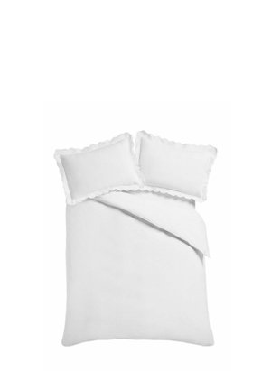 Weißes Bett mit zwei Kissen mit Rüschenrand und einer teilweise gefalteten weißen Bettdecke vor schlichtem Hintergrund.