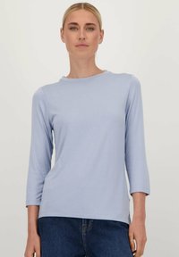 Lichtblauw, langemouwen top met een ronde halslijn, zachte textuur en een Relaxed fit. Voorzien van subtiele zijspleten aan de onderkant.