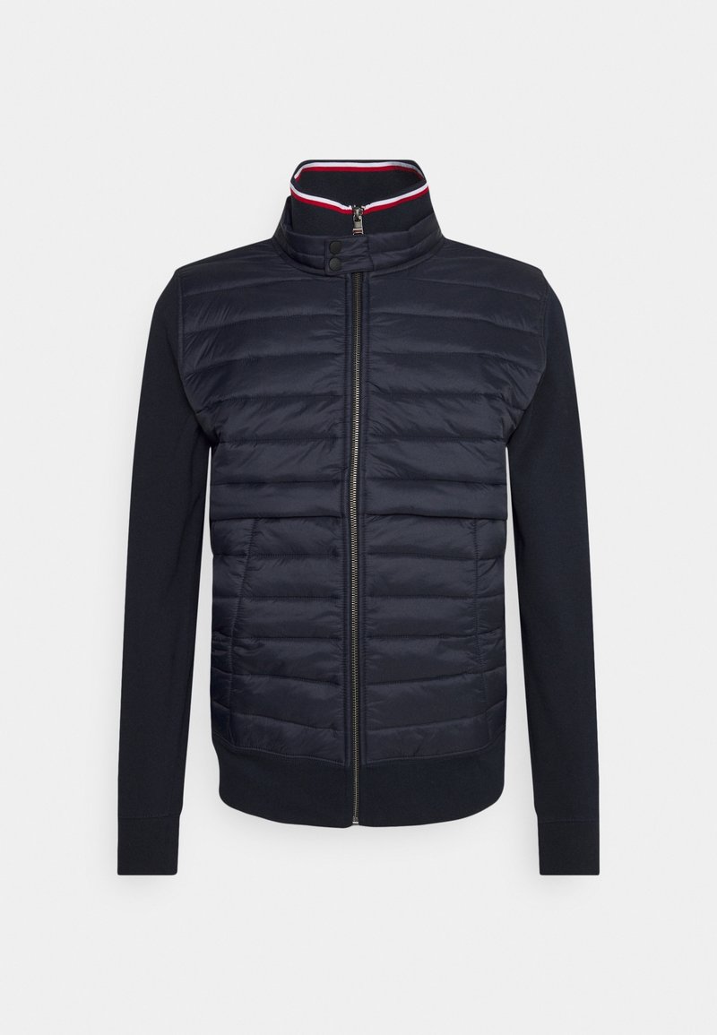 Veste bleu marine avec devant matelassé, fermeture éclair, col montant avec boutons-pression et manches longues lisses.