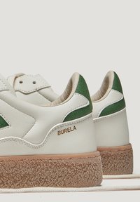 Baskets en cuir blanc avec des accents verts, semelles texturées et un logo. Conçues avec un bout arrondi et un col rembourré pour le confort.