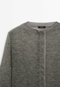 Harmaa neuleCardigan, jossa on pyöreä pääntie, pitkät hihat ja pystysuora nappirivi edessä, roikkumassa tasaisesti valkoisella taustalla.