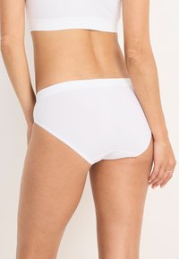 Vitt bomullsmixunderkläder med en slät textur, mid-rise design och bred midjeband. Har en enkel, sömlös snitt runt benen.
