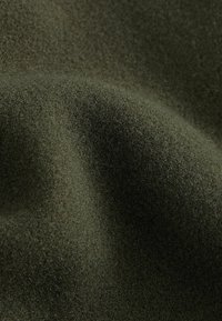 Dark green fabric with a soft, textured surface, displaying a fine, dense weave and subtle sheen.