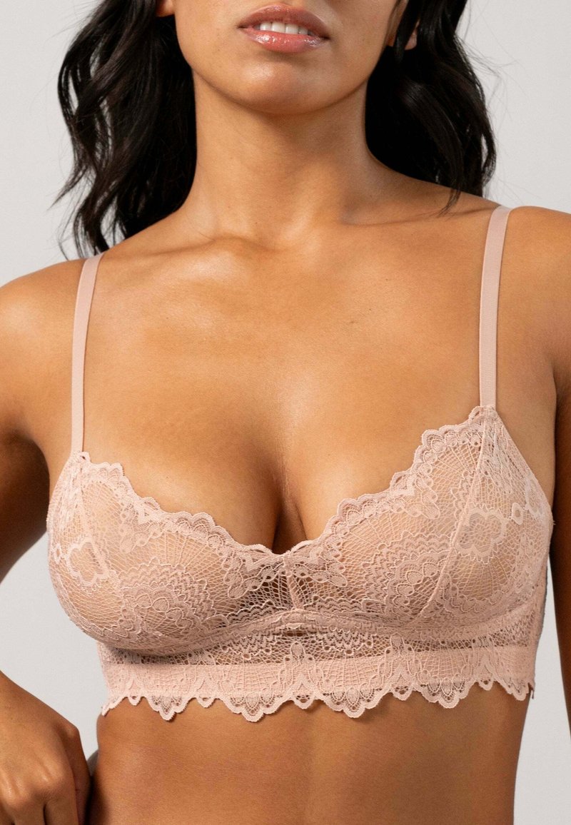 Spets-bh i ljusrosa med justerbara band, scallopade kanter och intrikata blommönster. Mjuk textur med en genomskinlig look.