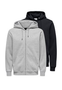 Twee hoodies tentoongesteld: de ene grijs met een rits, voorzakken en trekkoorden; de andere volledig zwart, beide met capuchons en ribbels aan de manchetten.