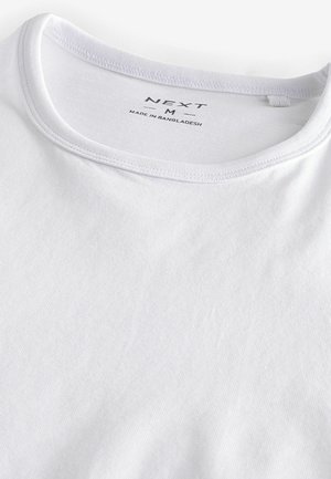 Vit bomull t-shirt med rund halsringning, med en mjuk textur och subtil ribbning vid kragen. Varumärkesetikett inuti halsen.