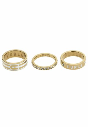 Trois anneaux en or : une bague logo blanche et dorée, une ornée de pierres claires, et une autre avec un accent blanc portant le logo.