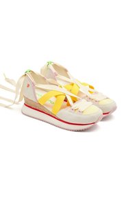 Zapatillas cuña en color beige claro con acentos en tonos pastel, que presentan tiras amarillas en forma de cruz, una suela intermedia texturizada y un borde rojo minimalista.