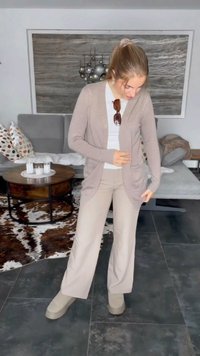 Lys beige cardigan med åpen front, lange ermer og sidelommer, kombinert med kremfargede vide bukser og beige slip-on sko.