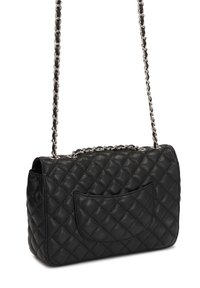 Black leather handbag with a quilted design, silver chain strap, and a front pocket. The texture is smooth, with a structured rectangular shape.