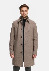 Bruine wolmix jas met een gestructureerde kraag, vijf knopen en zijzakken. Heeft een textuurafwerking en een getailleerde pasvorm.
