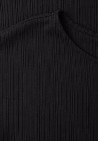 Gros plan sur un tissu noir côtelé avec des détails de couture en diagonale, montrant la texture et les points.