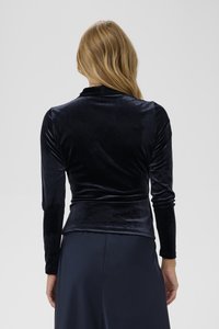 Maglia a maniche lunghe in velluto blu scuro con silhouette aderente, leggermente arricciata in vita, texture liscia e collo alto.
