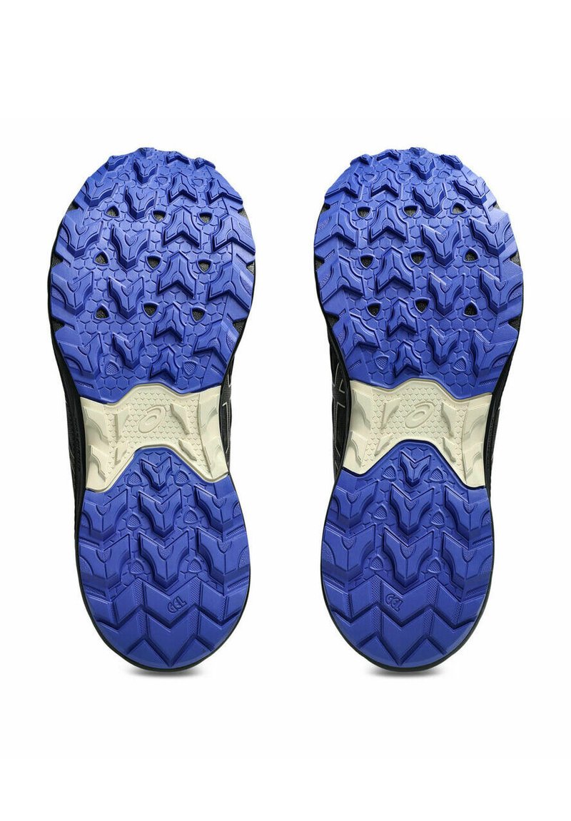 Suelas de zapatillas deportivas negras con una superficie texturizada. Goma azul oscuro con un patrón de dibujo distintivo y un acento de entresuela blanca a lo largo del centro.