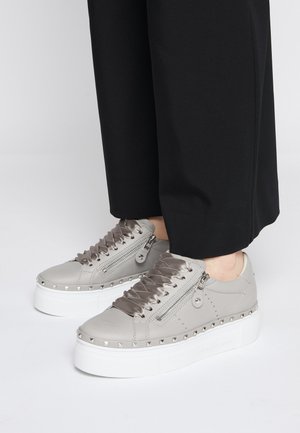 Baskets à plateforme grises avec lacets en ruban, fermeture éclair latérale et détails cloutés, portées avec un pantalon noir court.