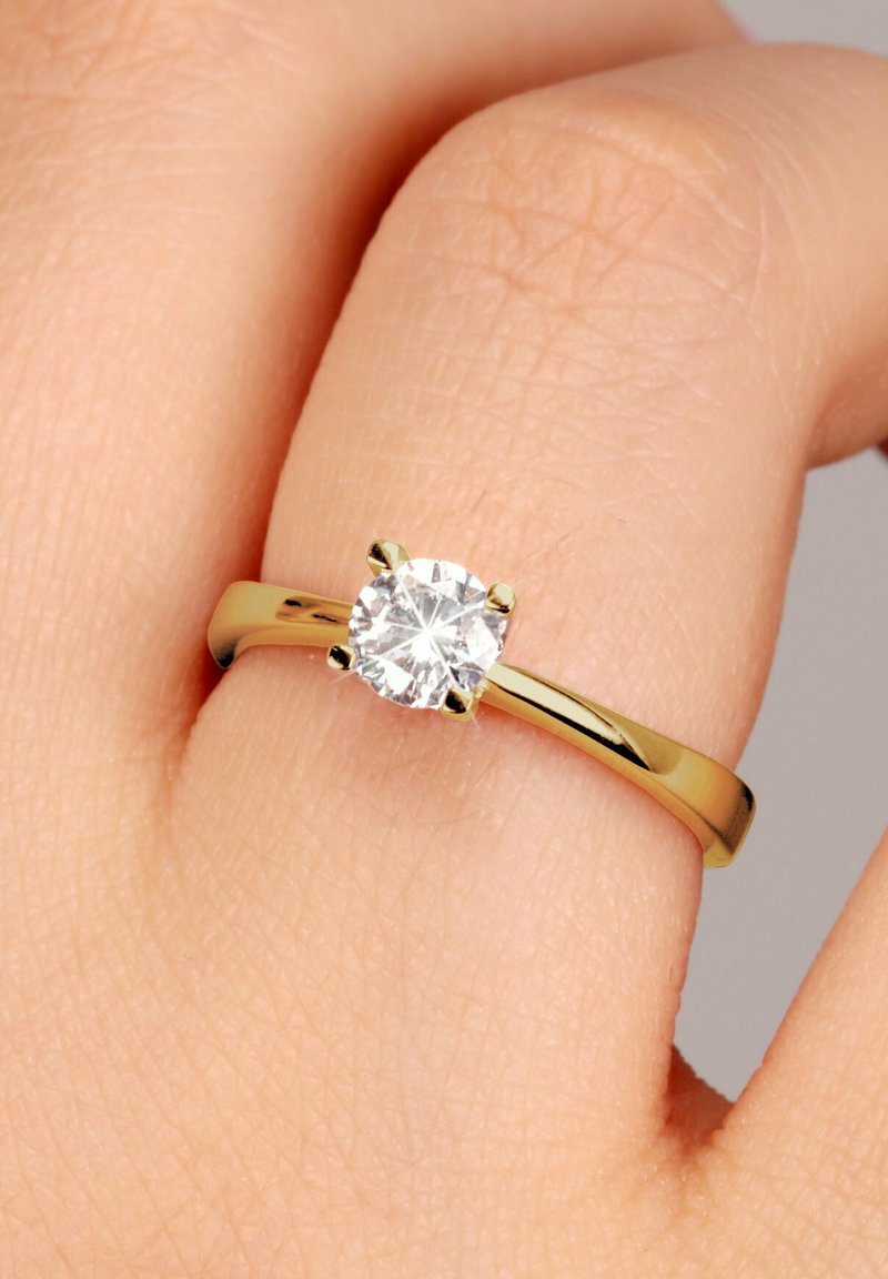 Goldring mit einem zentralen klaren runden Diamanten, der in sechs Krappen gefasst ist, und einem glatten, polierten Band, das ein glänzendes Finish aufweist.