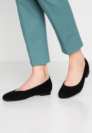 Czarne baleriny zamszowe o szpiczastym czubku i niskim obcasie, zestawione z turkusowymi, skróconymi spodniami. Gładka faktura, minimalistyczny styl.
