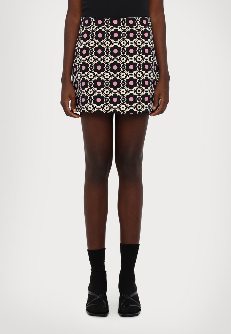 Minirock mit Blumenmuster in Pink-, Schwarz- und Cremefarben. Verfügt über einen elastischen Bund und ein enges Design. Kombiniert mit schwarzen Kniestrümpfen und Schuhen.