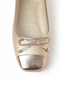 Bailarina dorada con punta redondeada, con una tapa dorada brillante y un lazo ornamental con puntas de metal en la parte superior. Textura suave en todo.
